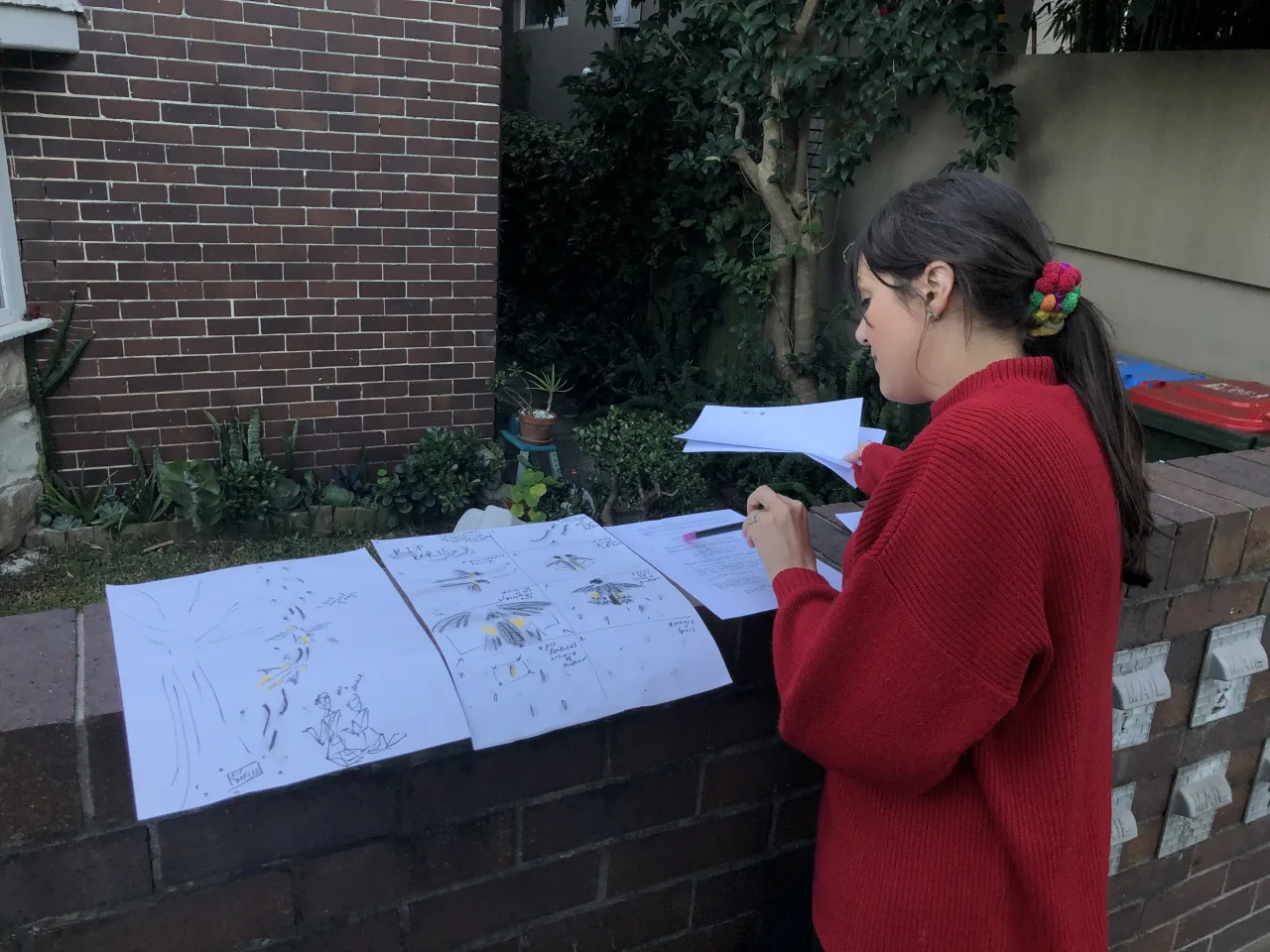 Jenna Sutch looks over drawings laid out along a garden wall